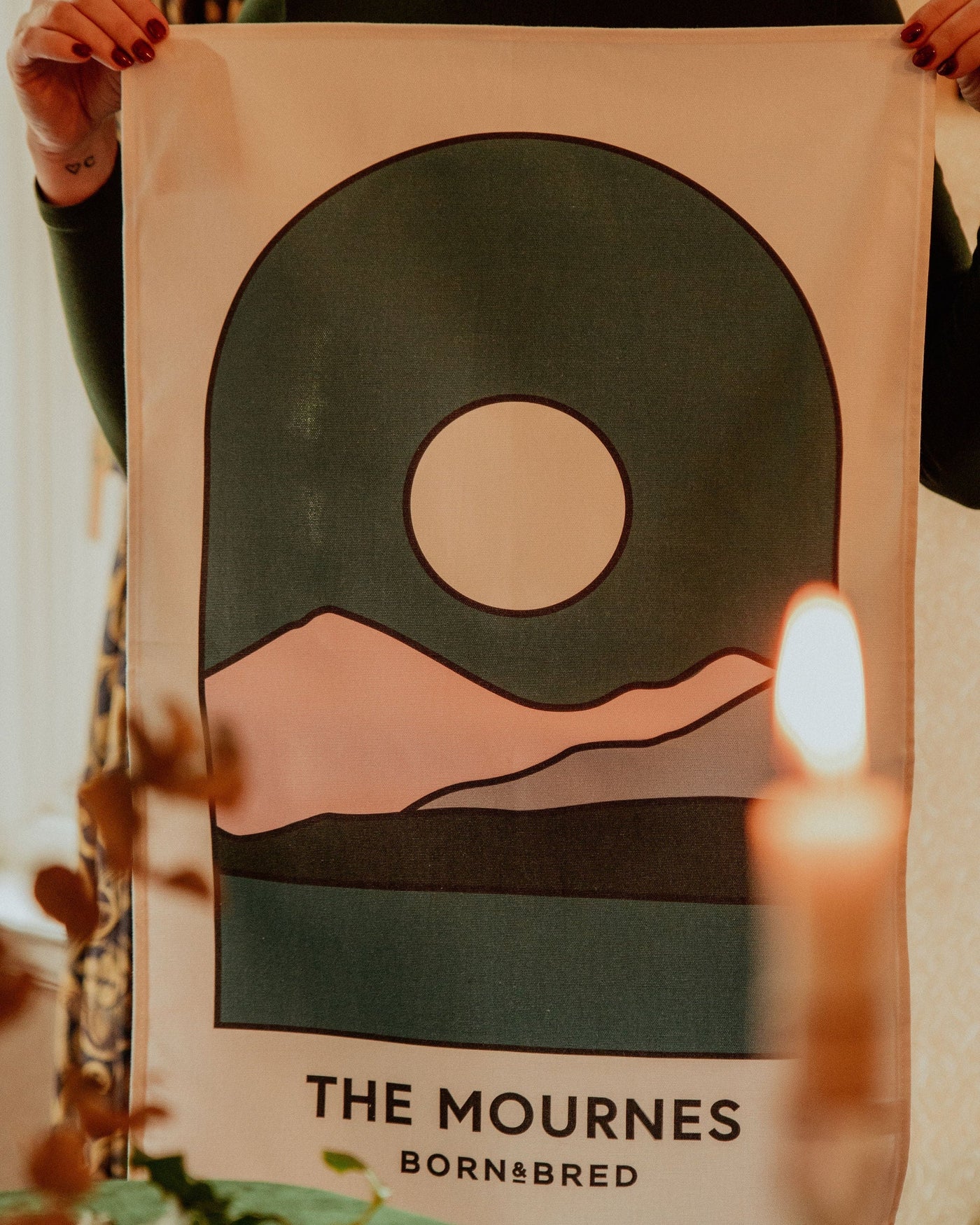 Person holding a poster with abstract design and 'The Mournes' branding.